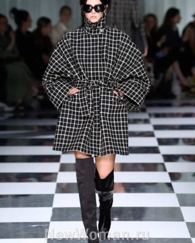осеннее женское пальто 2025 года в черно-белую клетку выше колена с черными высокими сапогами